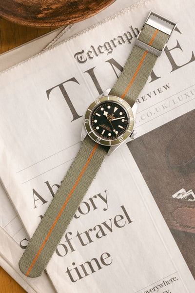 TUDOR Black Bay GMT 41mm - Harrods Green fitted with Elliot Brown webbing strap in grey green flat on newspaper